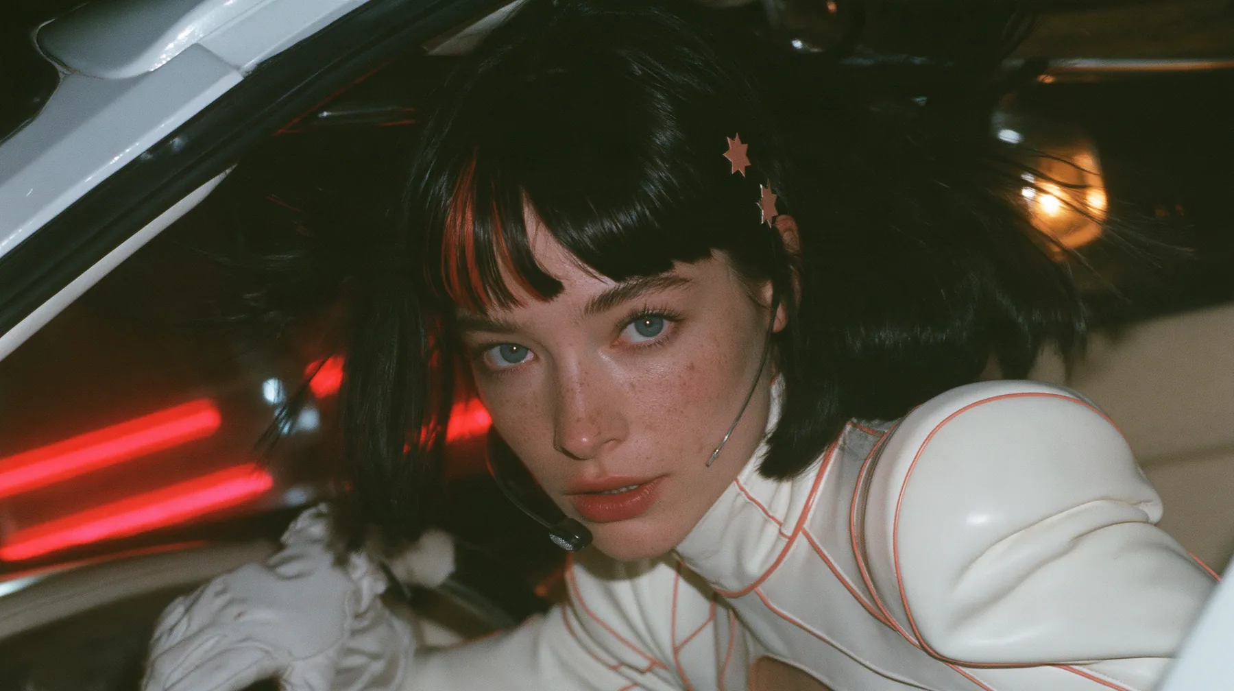 medium close-up, a 28-year-old Caucasian American woman with a grown-up angular face, defined cheekbones and a strong jawline, pale skin and light freckles, a glossy black blunt jaw-length bob with heavy straight…