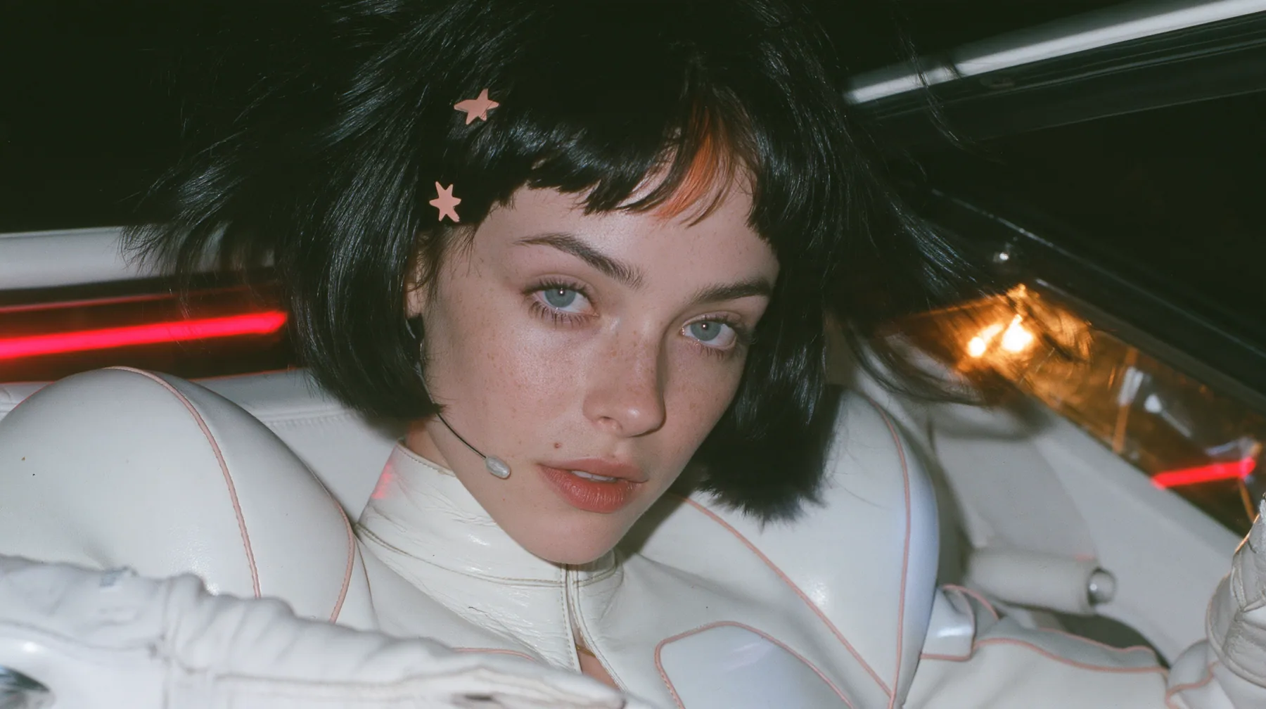 medium close-up, a 28-year-old Caucasian American woman with a grown-up angular face, defined cheekbones and a strong jawline, pale skin and light freckles, a glossy black blunt jaw-length bob with heavy straight…