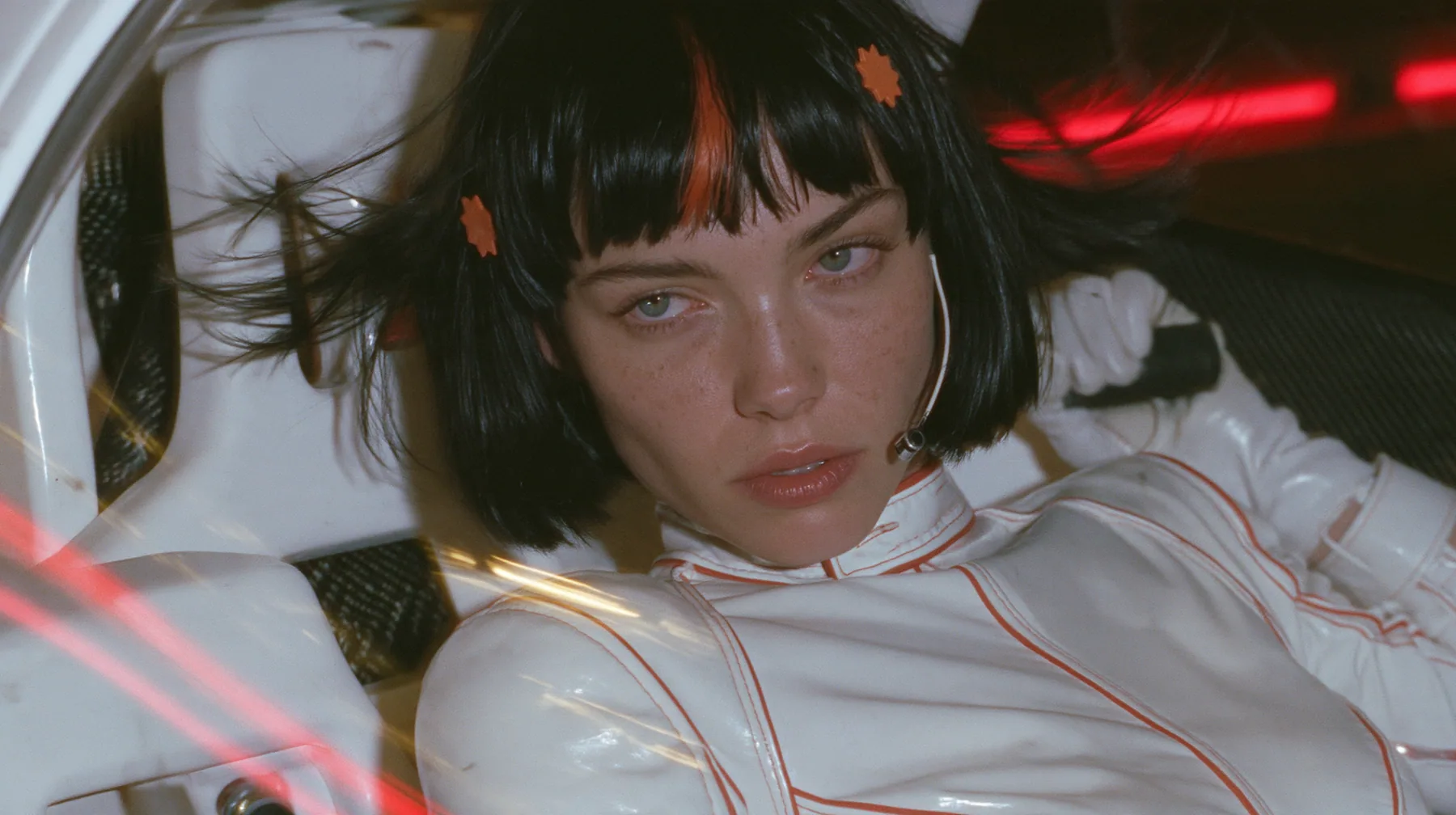 close-up, eye level, a 28-year-old Caucasian American woman with a grown-up angular face, defined cheekbones and a strong jawline, pale skin and light freckles, a glossy black blunt jaw-length bob with heavy straight…