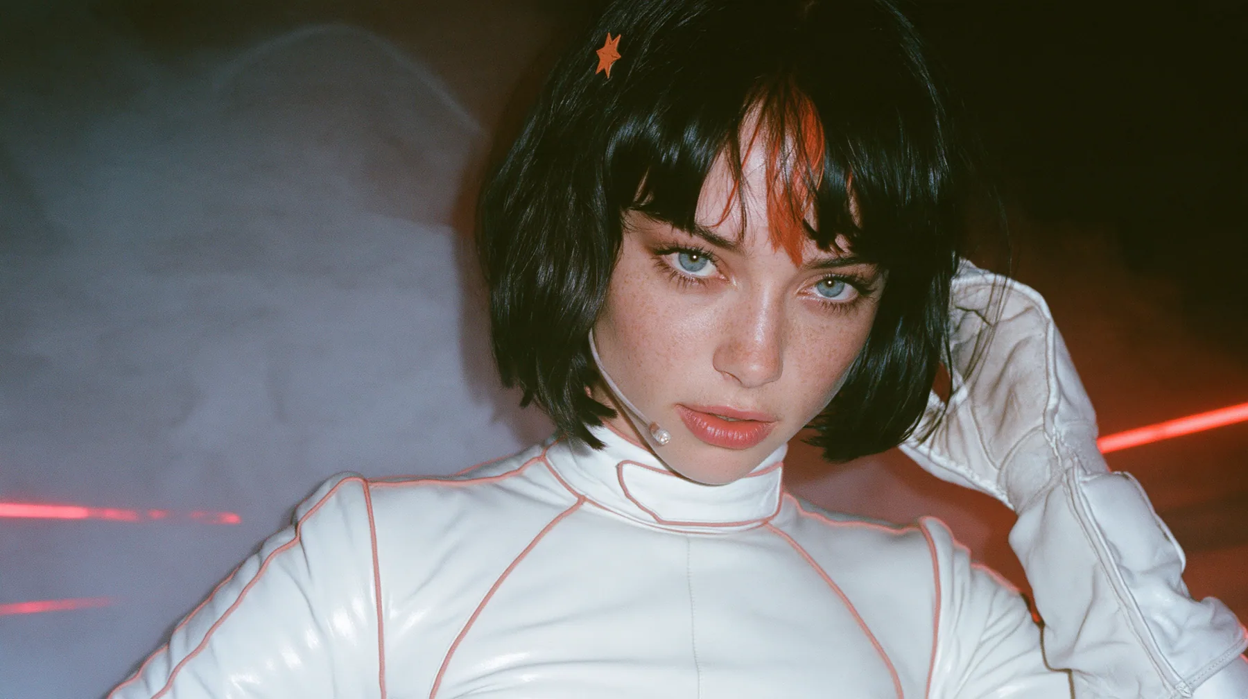 close-up, eye level, looking straight into the lens, a 28-year-old Caucasian American woman with a grown-up angular face, defined cheekbones and a strong jawline, pale skin and light freckles, a glossy black blunt…