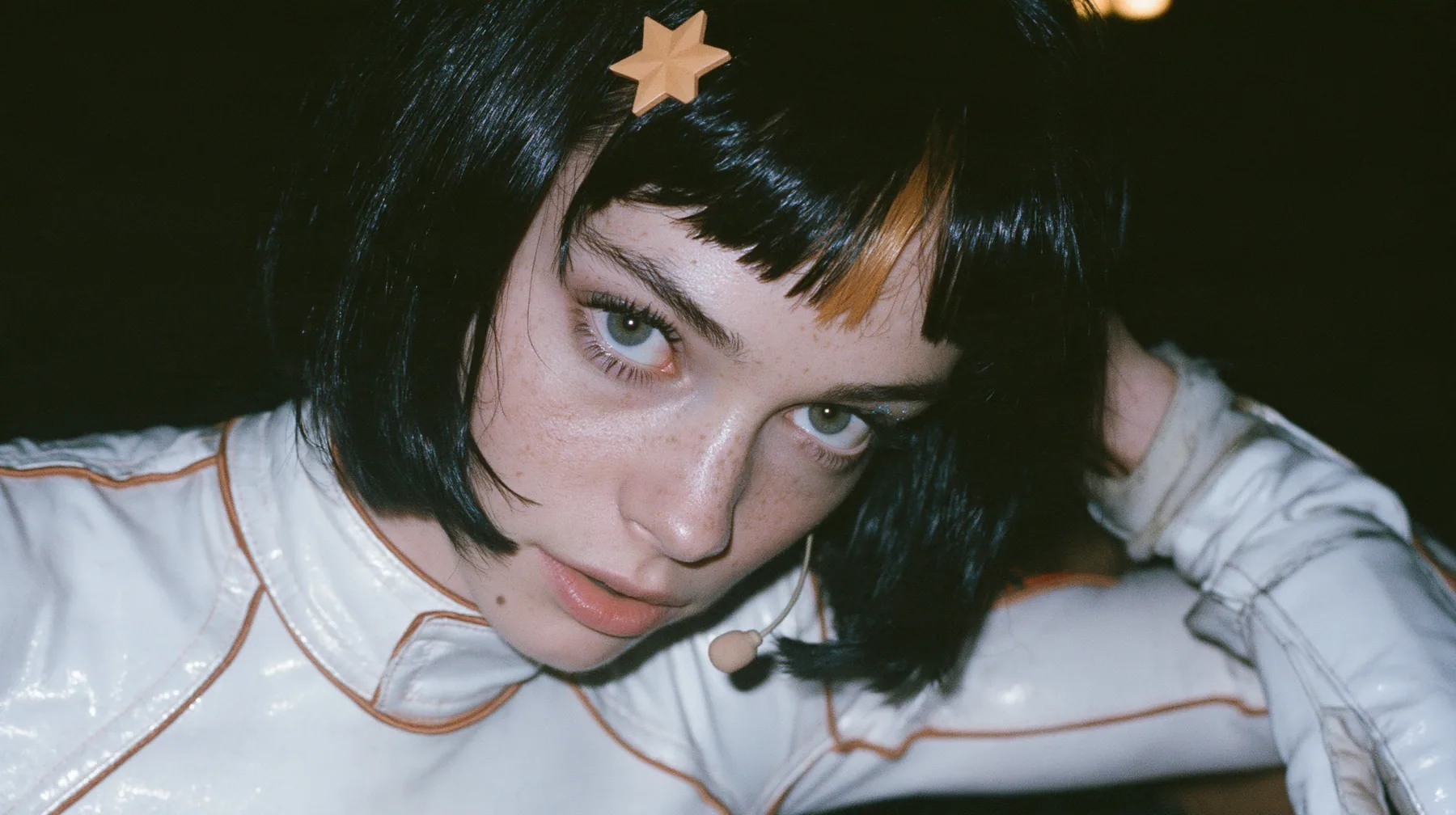 close-up portrait, eye level, a 28-year-old Caucasian American woman with a grown-up angular face, defined cheekbones and a strong jawline, pale skin and light freckles, a glossy black blunt jaw-length bob with heavy…