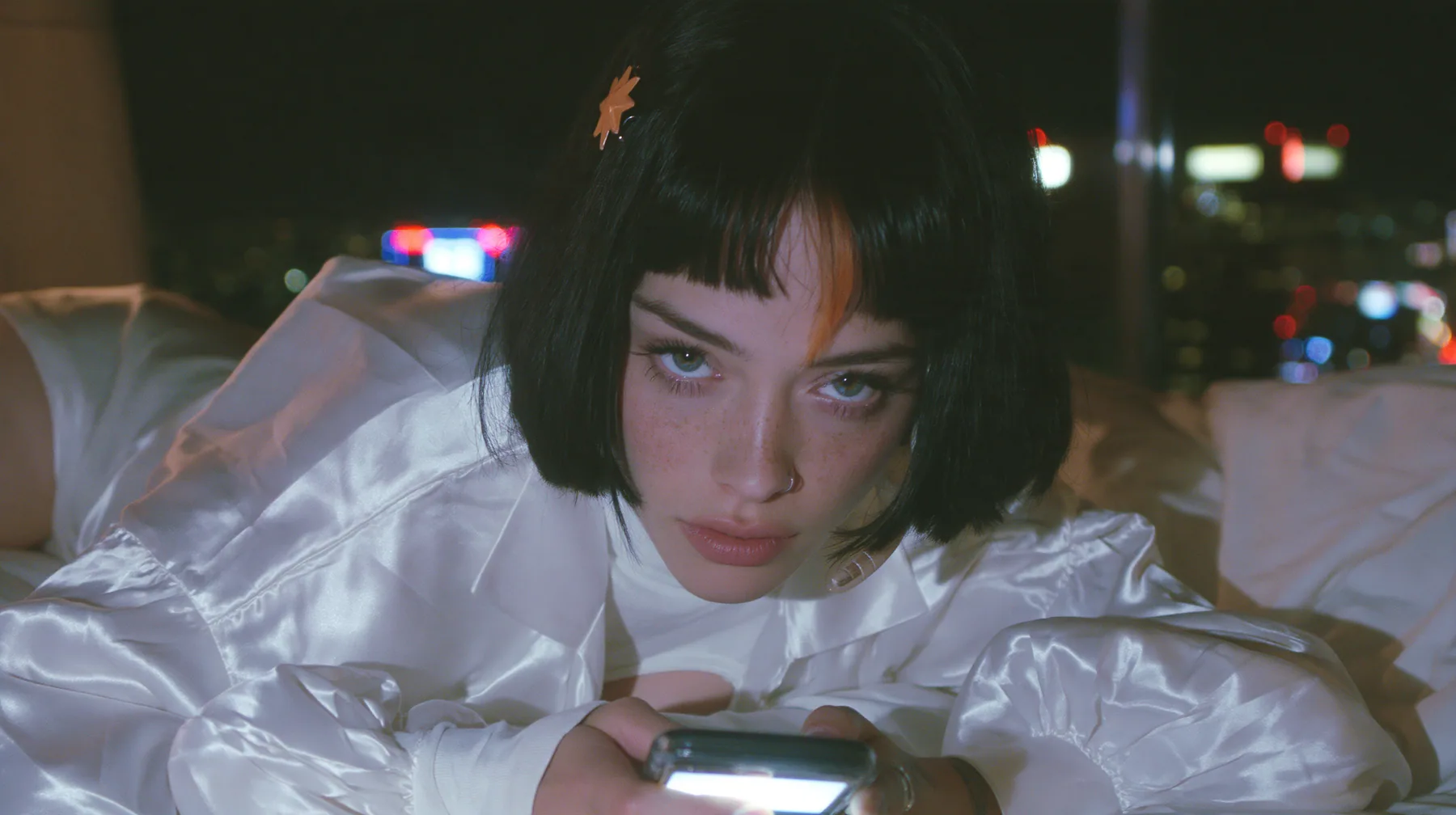medium shot at mattress height, a 28-year-old Caucasian American woman with a grown-up angular face, defined cheekbones and a strong jawline, pale skin and light freckles, a glossy black blunt jaw-length bob with…