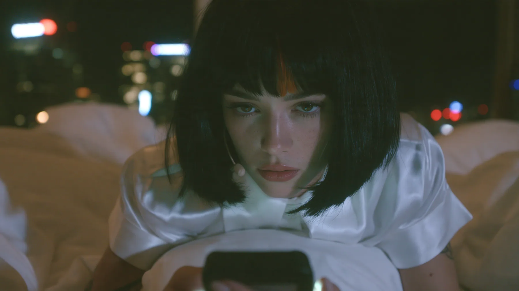 medium shot at mattress height, a 28-year-old Caucasian American woman with a grown-up angular face, defined cheekbones and a strong jawline, pale skin and light freckles, a glossy black blunt jaw-length bob with…