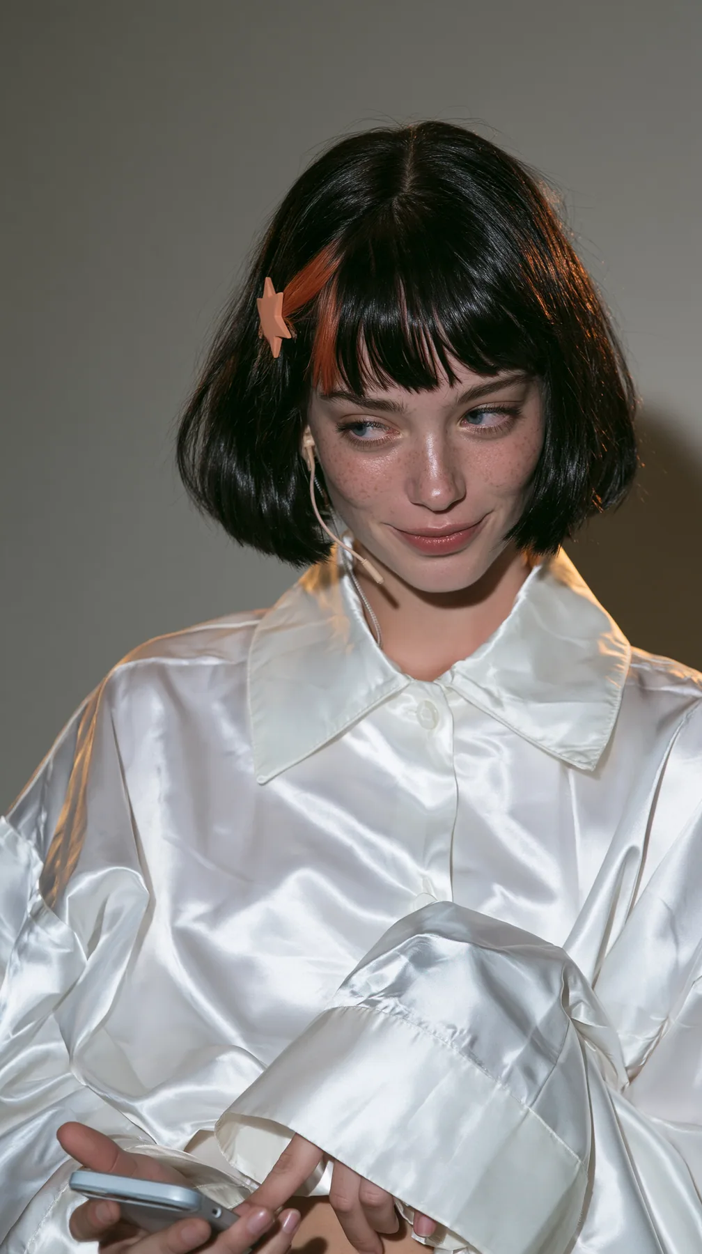 medium-full shot, a 28-year-old Caucasian American woman with a grown-up angular face, defined cheekbones and a strong jawline, pale skin and light freckles, a glossy black blunt jaw-length bob with heavy straight…