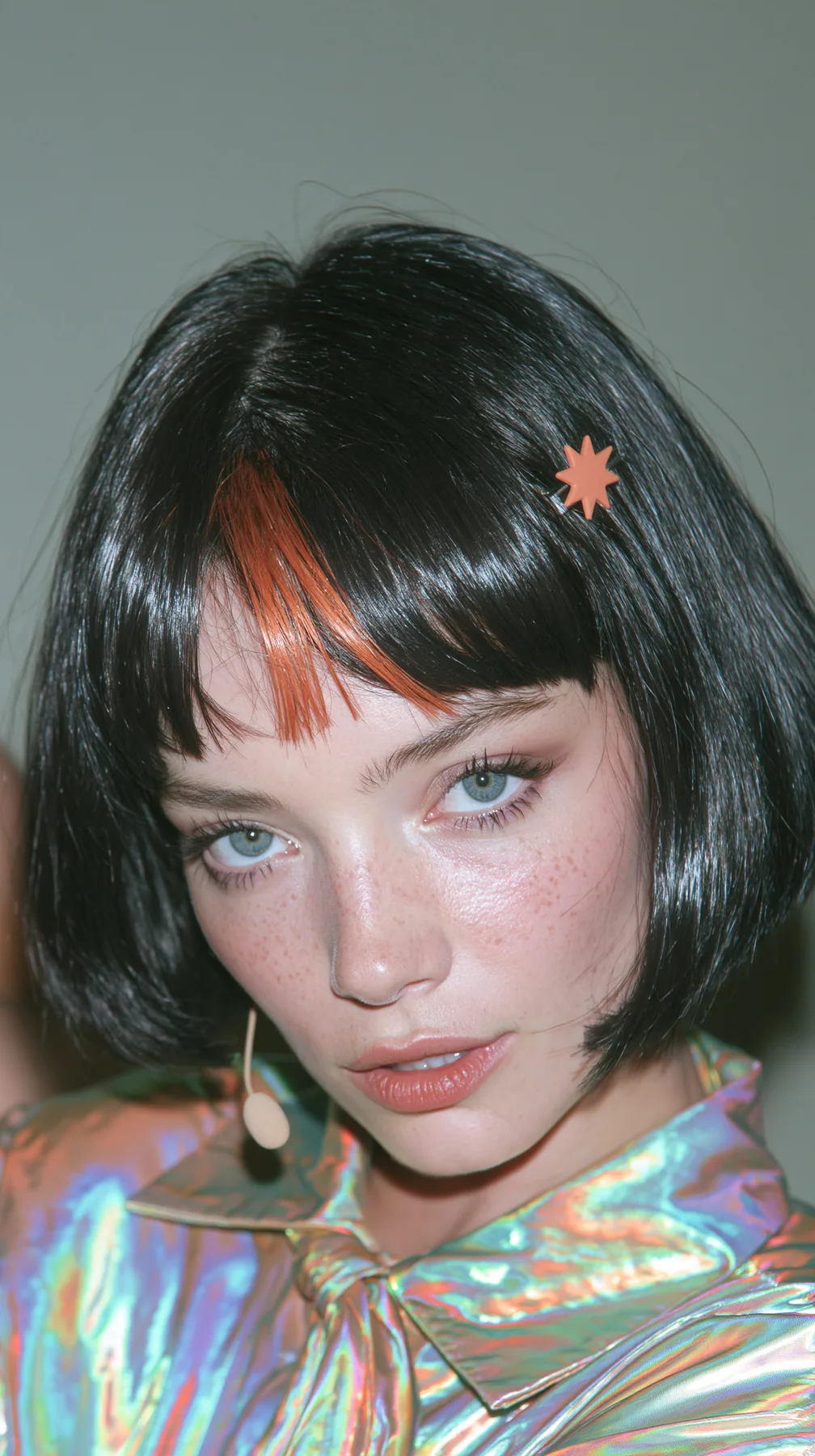 medium-full shot, a 28-year-old Caucasian American woman with a grown-up angular face, defined cheekbones and a strong jawline, pale skin and light freckles, a glossy black blunt jaw-length bob with heavy straight…