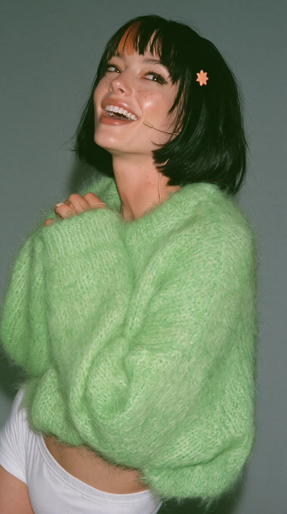 medium-full shot, a 28-year-old Caucasian American woman with a grown-up angular face, defined cheekbones and a strong jawline, pale skin and light freckles, a glossy black blunt jaw-length bob with heavy straight…
