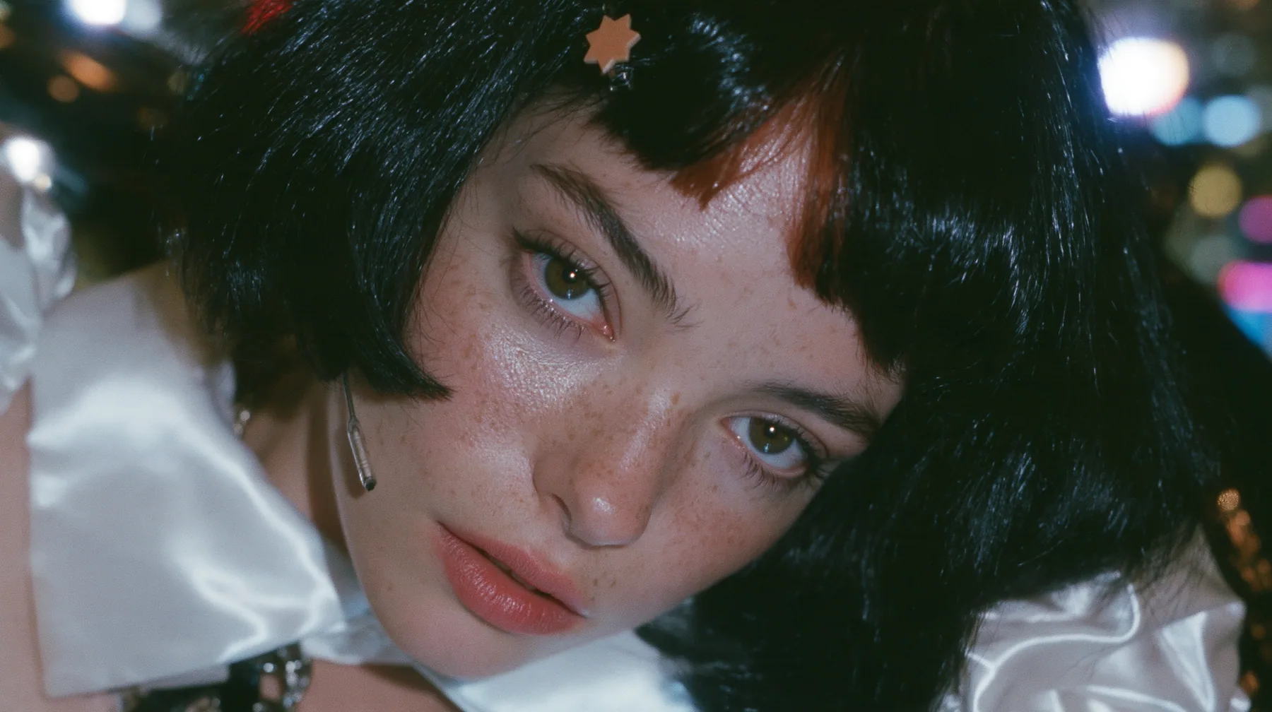close-up, a 28-year-old Caucasian American woman with a grown-up angular face, defined cheekbones and a strong jawline, pale skin and light freckles, a glossy black blunt jaw-length bob with heavy straight bangs and…