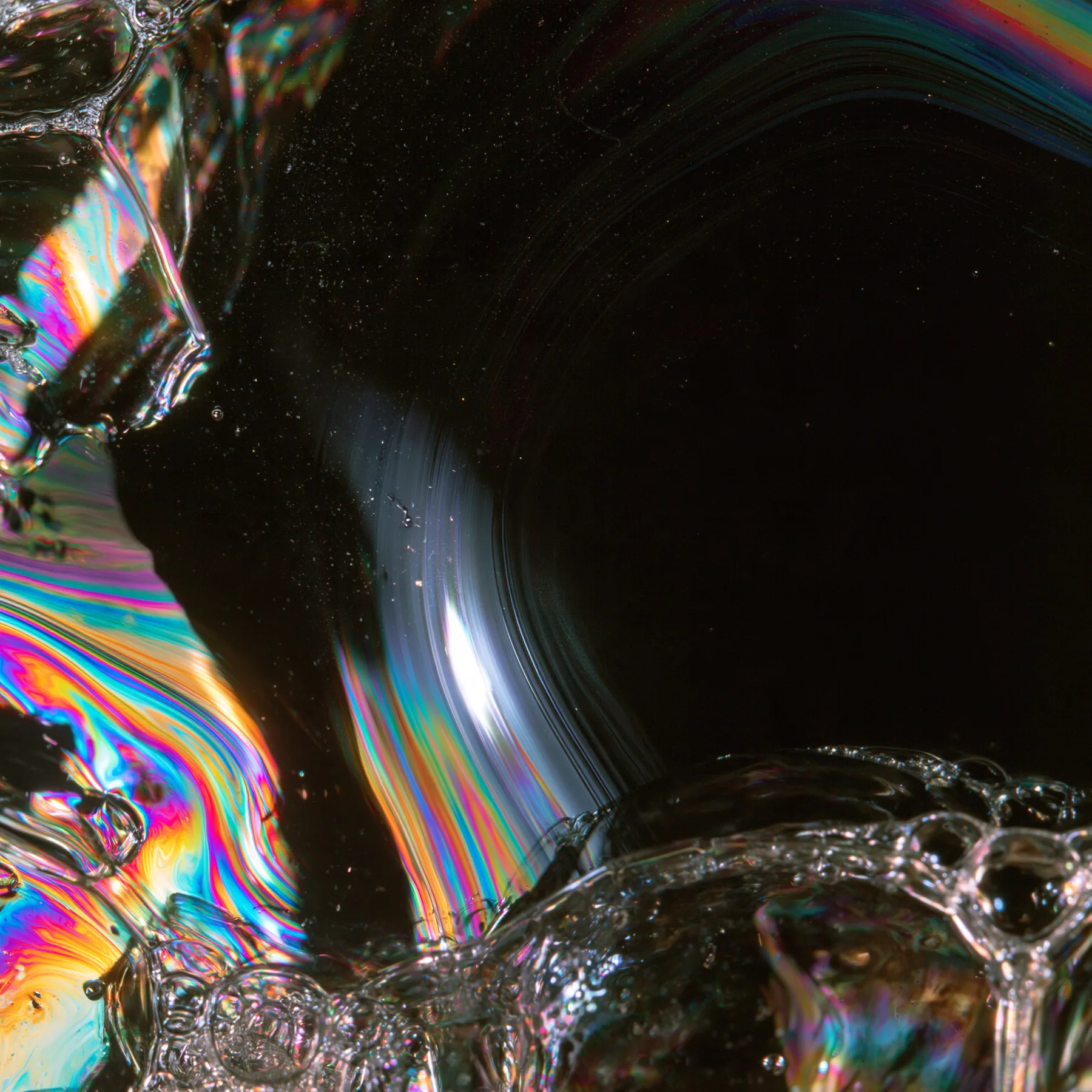 macro of a soap film with swirling iridescent interference colours on black, scientific photograph, no text, no letters, no logos