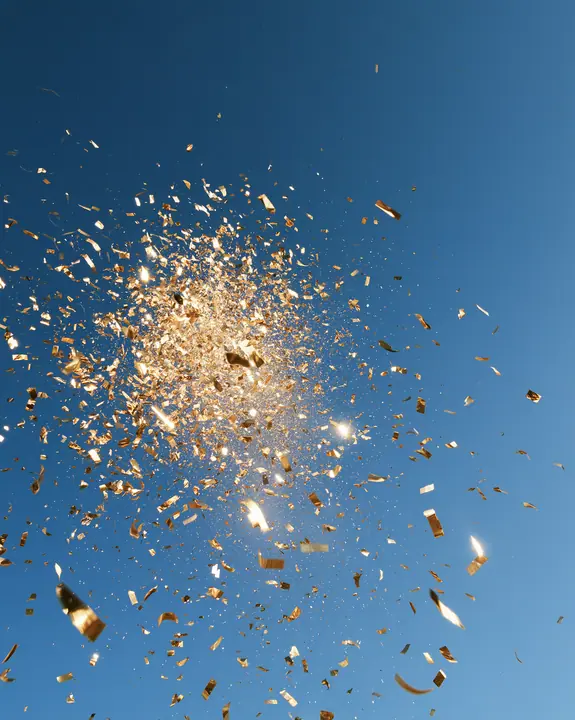 a burst of gold confetti against a clear blue sky, celebration, crisp, no text, no letters, no logos