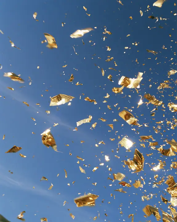 a burst of gold confetti against a clear blue sky, celebration, crisp, no text, no letters, no logos