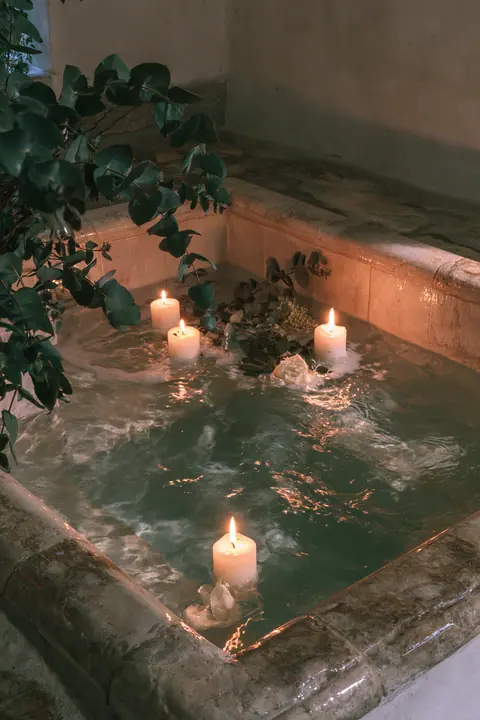 a sunken stone bathtub with candles and eucalyptus, warm evening light, no text, no letters, no logos