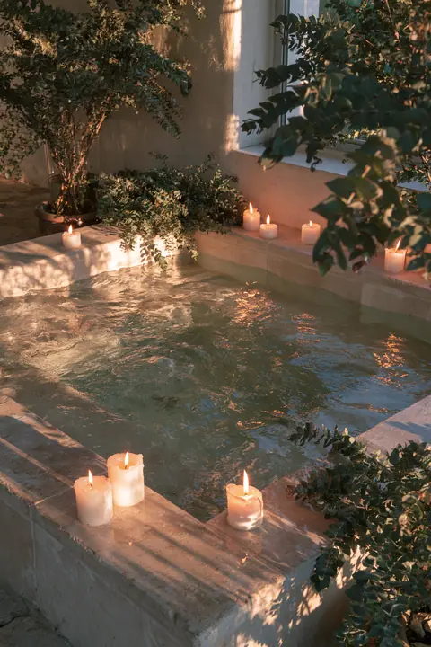 a sunken stone bathtub with candles and eucalyptus, warm evening light, no text, no letters, no logos