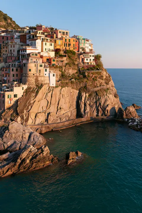 a Mediterranean cliffside village of pastel houses at sunset above a turquoise sea, no text, no letters, no logos