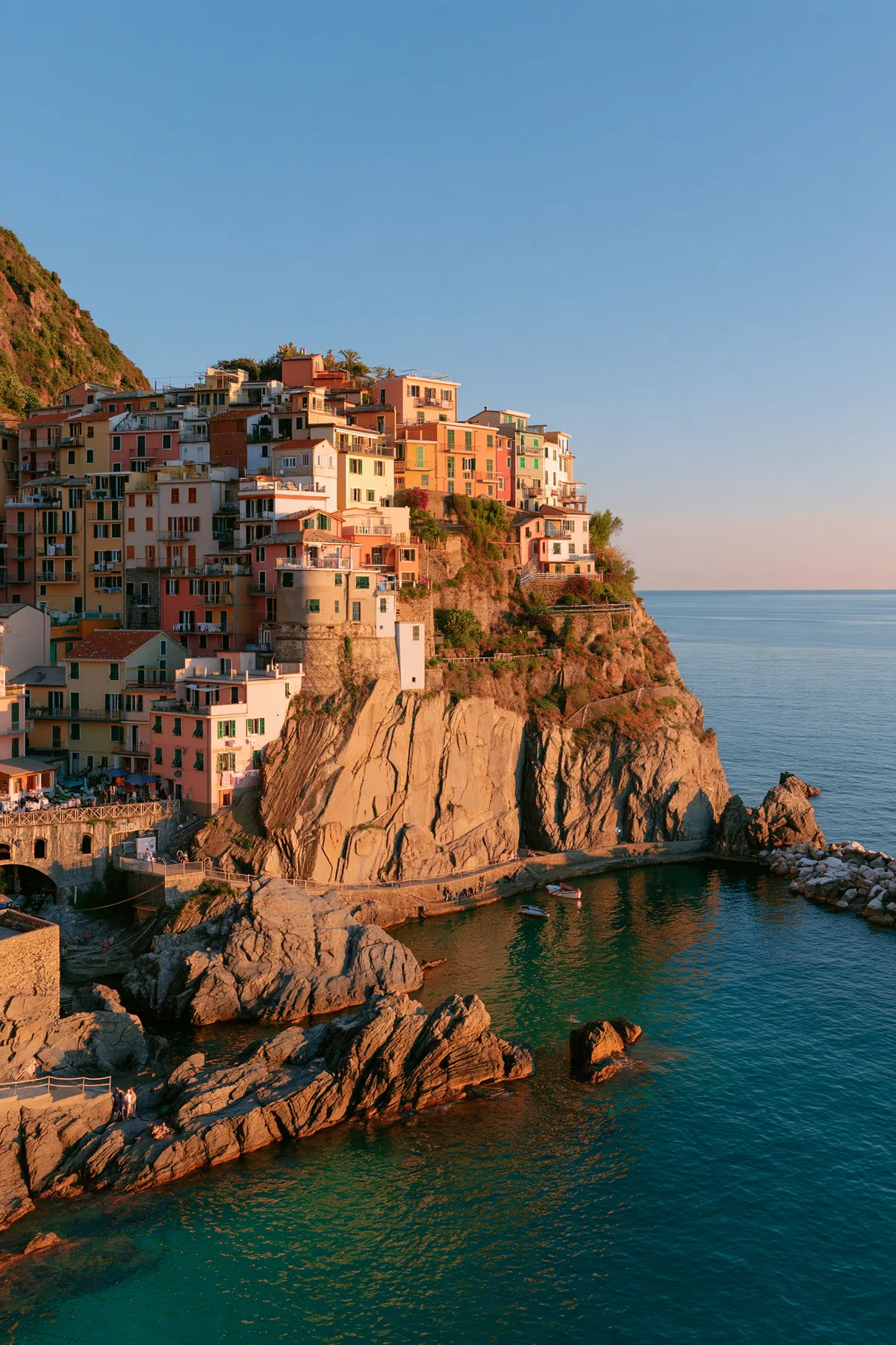 a Mediterranean cliffside village of pastel houses at sunset above a turquoise sea, no text, no letters, no logos