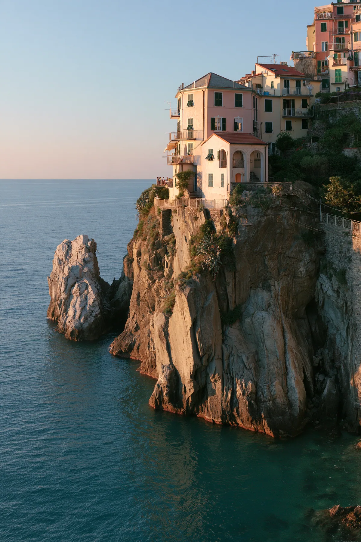 a Mediterranean cliffside village of pastel houses at sunset above a turquoise sea, no text, no letters, no logos