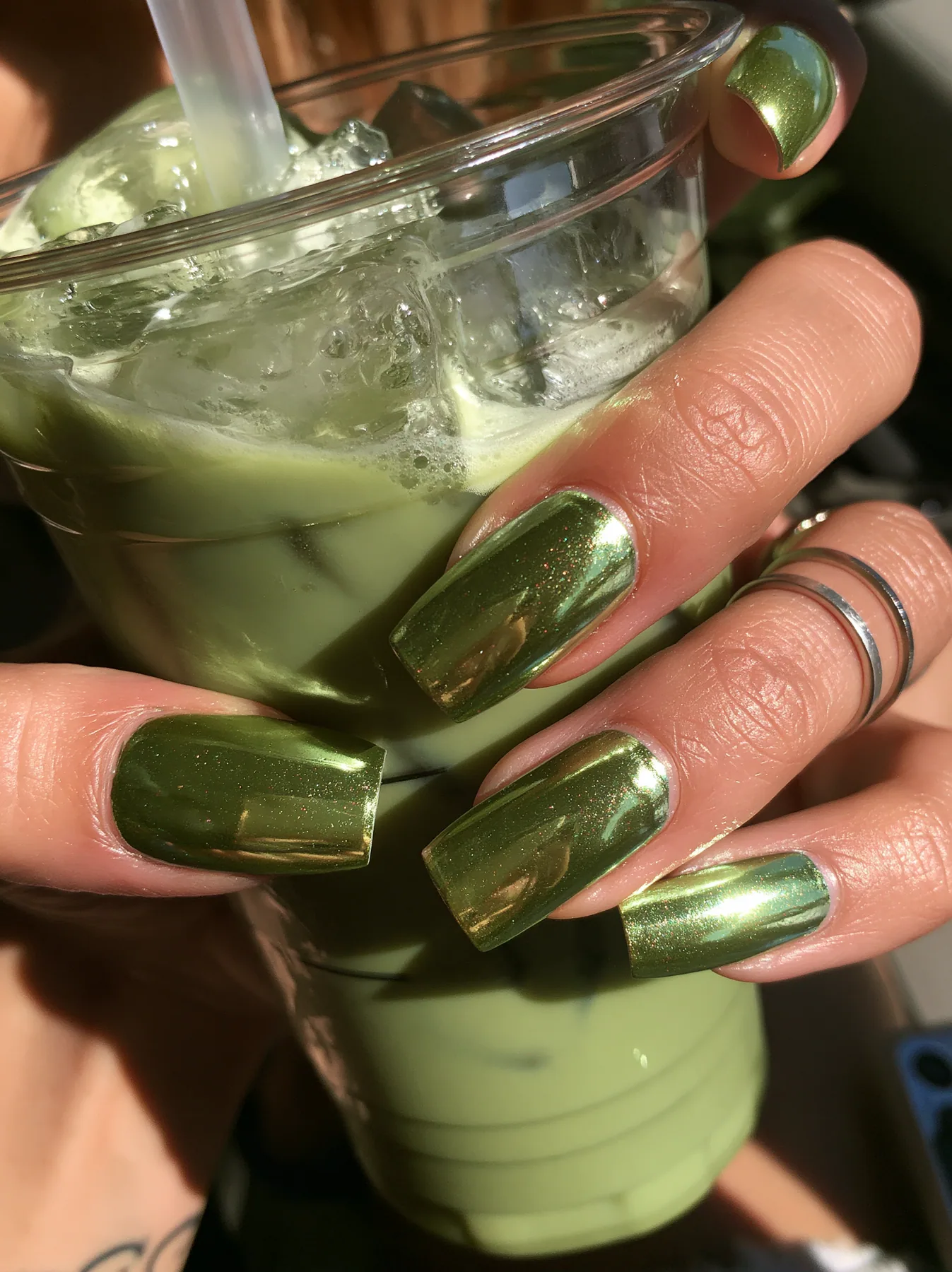 chrome-polished nails holding an iced matcha latte, close-up, sunlight, no text, no letters, no logos