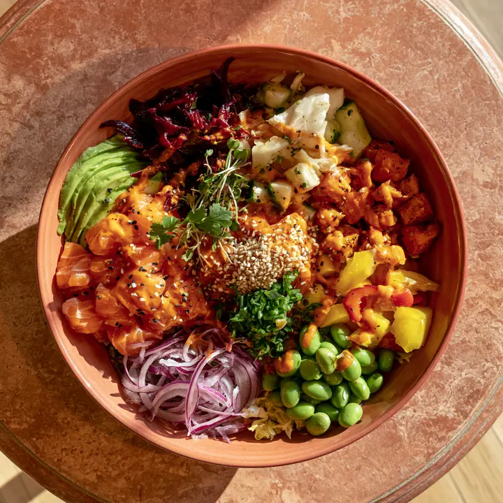 a colourful poke bowl from above on a terracotta table, natural light, no text, no letters, no logos