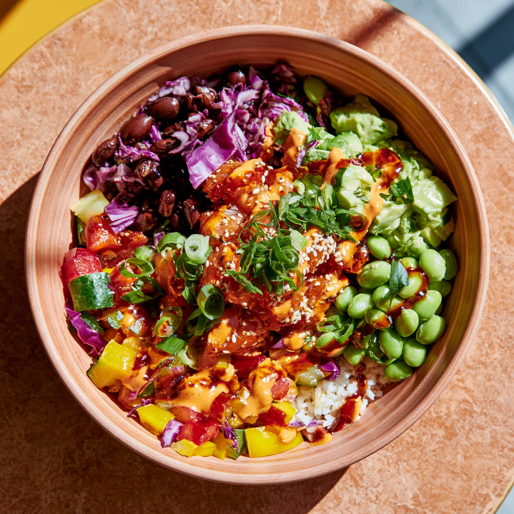 a colourful poke bowl from above on a terracotta table, natural light, no text, no letters, no logos