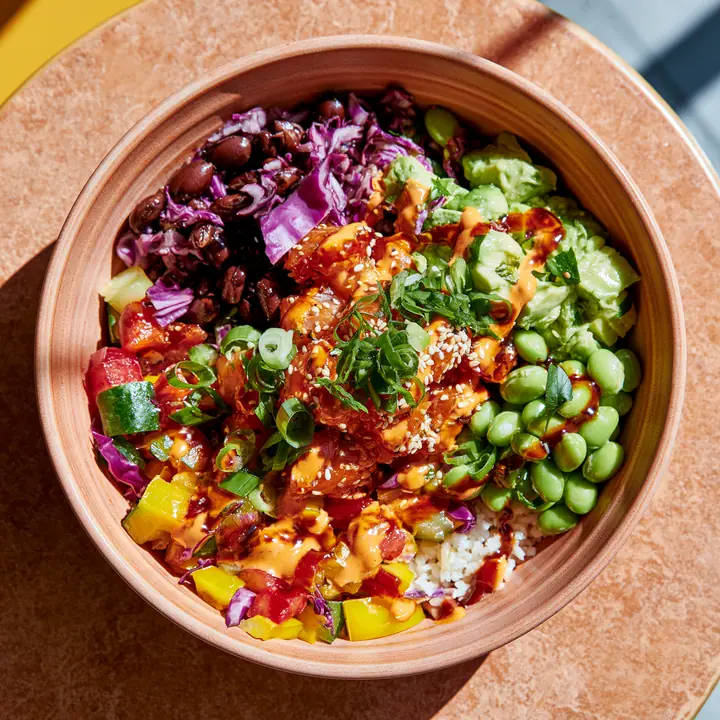 a colourful poke bowl from above on a terracotta table, natural light, no text, no letters, no logos
