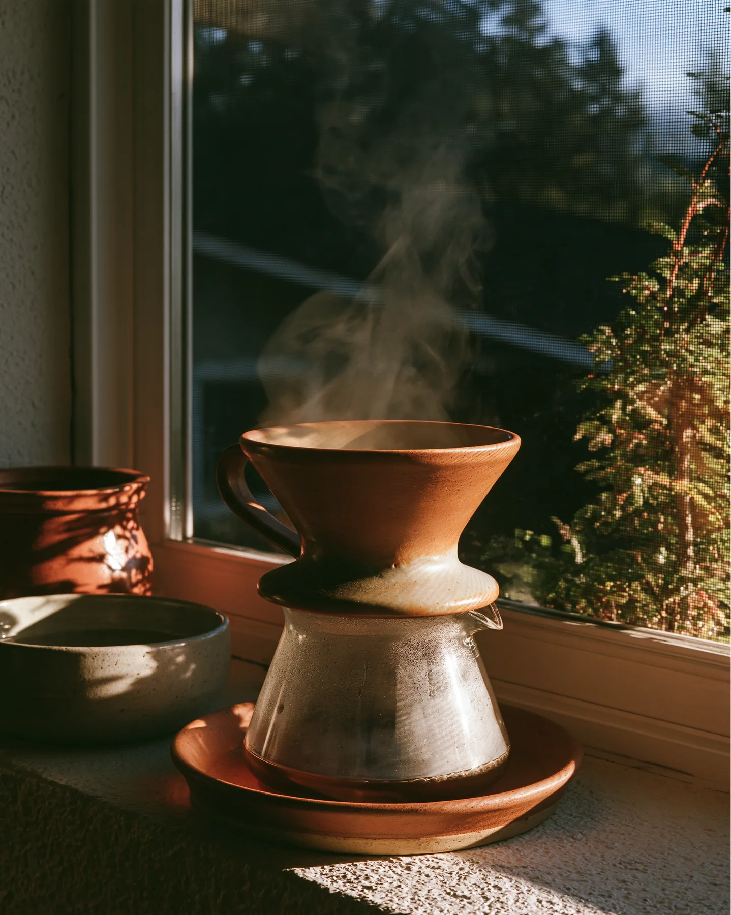 a ceramic pour-over coffee set on a windowsill at dawn, steam, no text, no letters, no logos