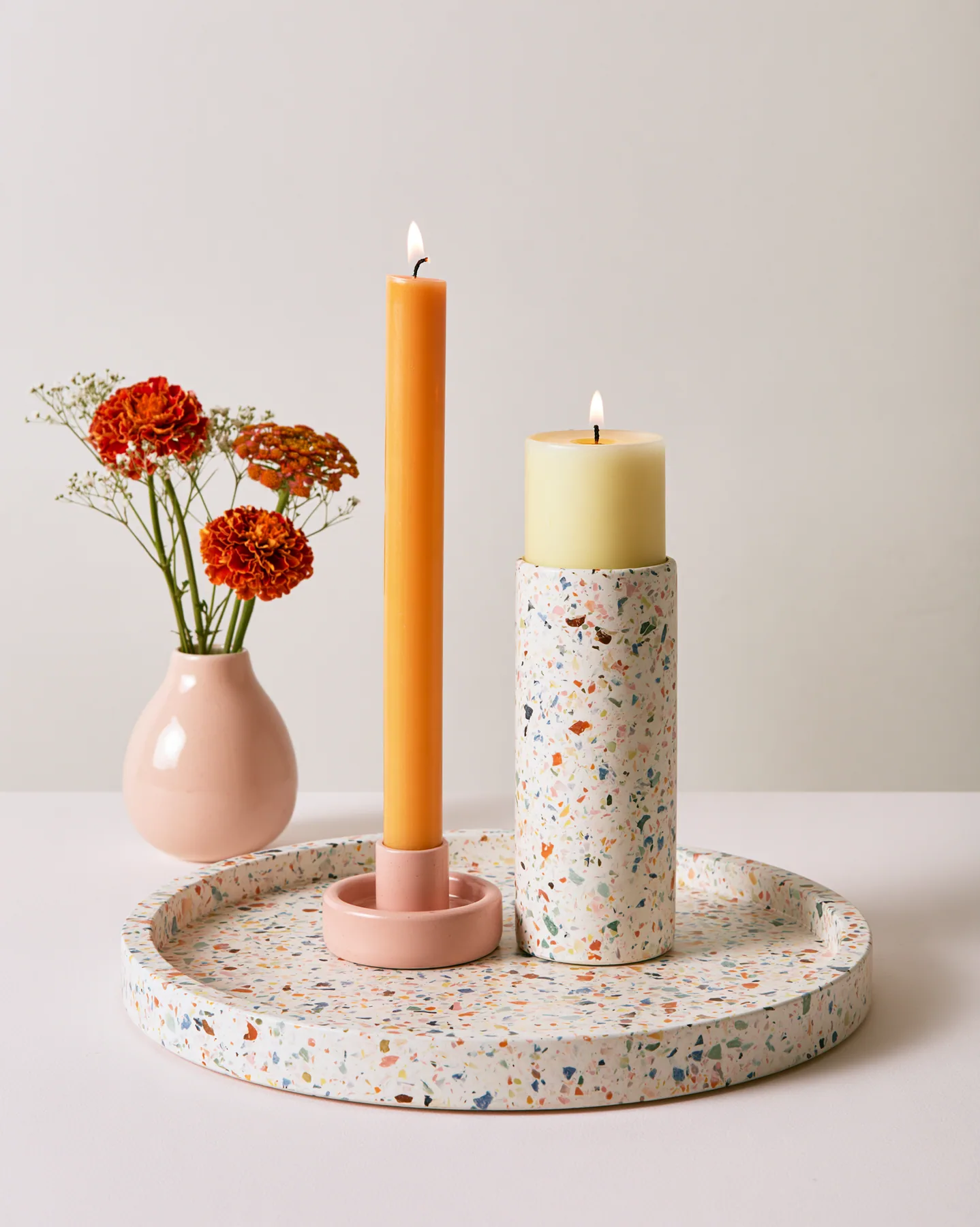 a pastel terrazzo tray with candles and a small vase, styled still life, no text, no letters, no logos