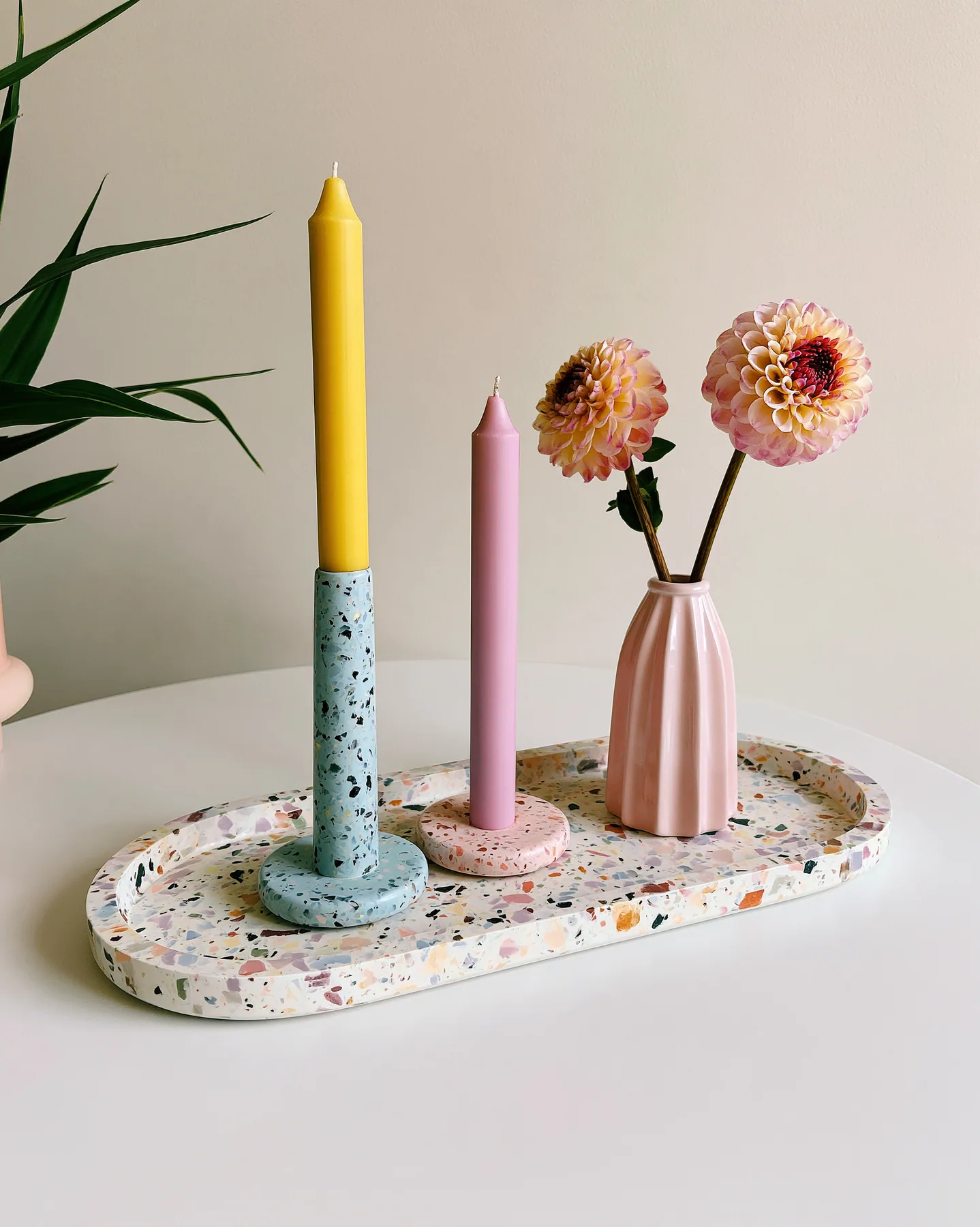 a pastel terrazzo tray with candles and a small vase, styled still life, no text, no letters, no logos