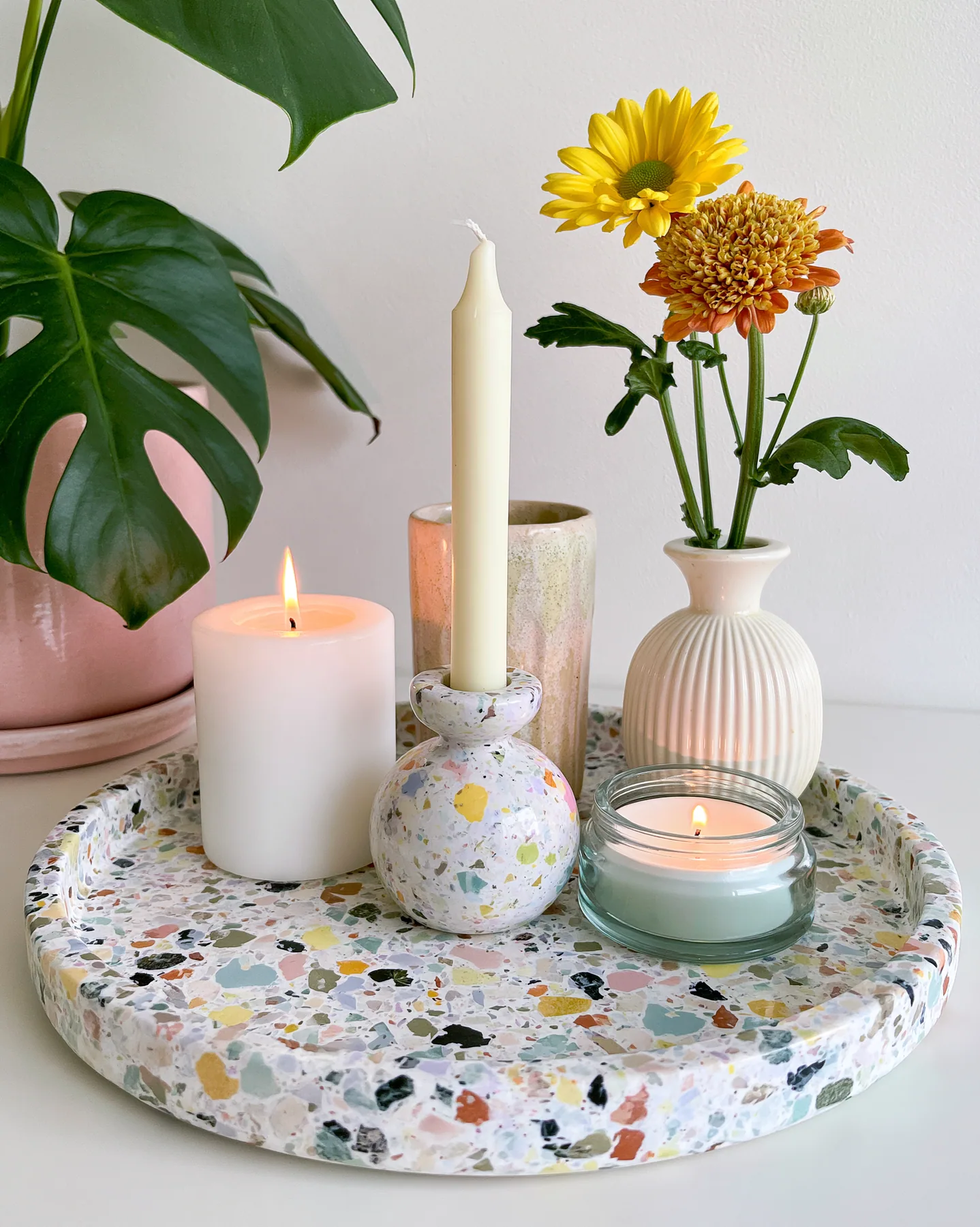 a pastel terrazzo tray with candles and a small vase, styled still life, no text, no letters, no logos
