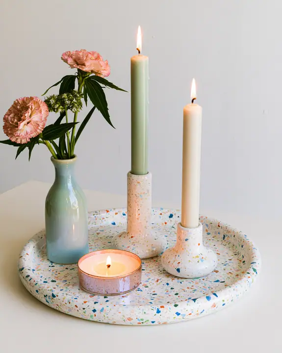 a pastel terrazzo tray with candles and a small vase, styled still life, no text, no letters, no logos