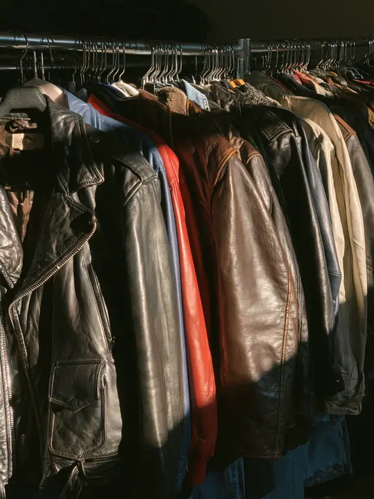 a rack of vintage leather jackets in a sunlit thrift shop, no text, no letters, no logos