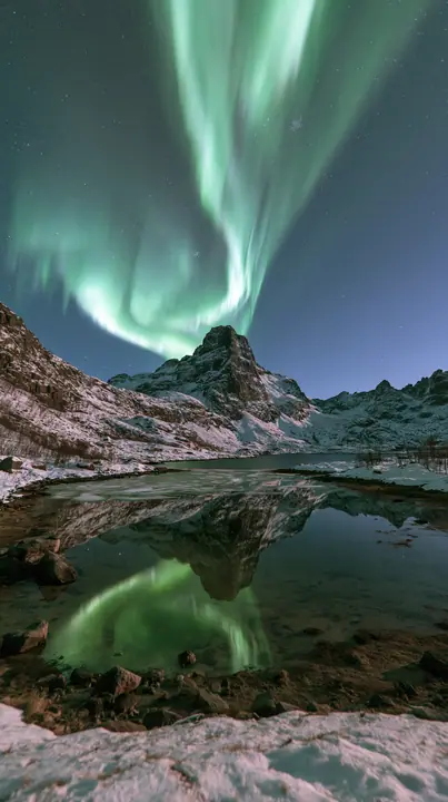 the northern lights rippling green and violet over a snowy mountain lake, no text, no letters, no logos