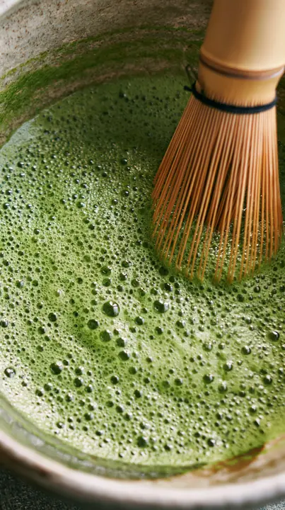 matcha being whisked in a ceramic bowl, bright green foam, overhead, no text, no letters, no logos