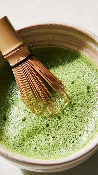 matcha being whisked in a ceramic bowl, bright green foam, overhead, no text, no letters, no logos