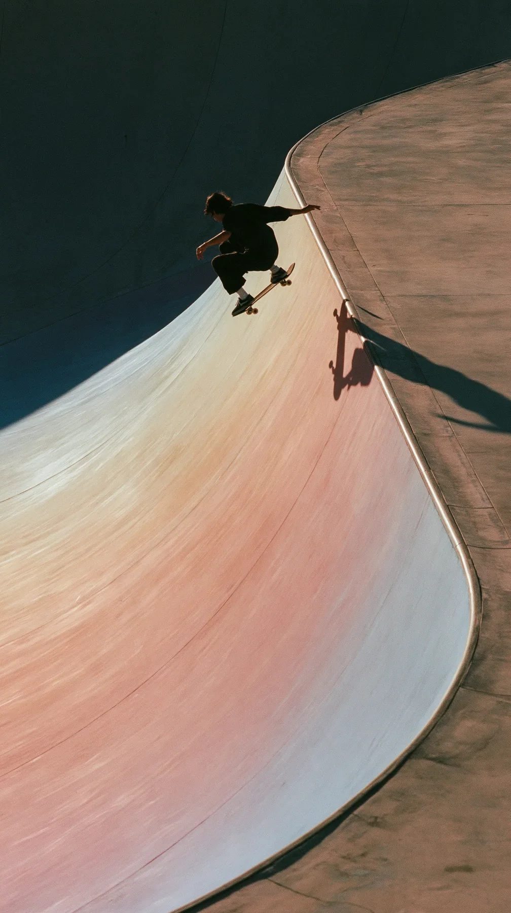 a skateboarder mid-ollie over a pastel concrete ramp at sunset, long shadows, no text, no letters, no logos