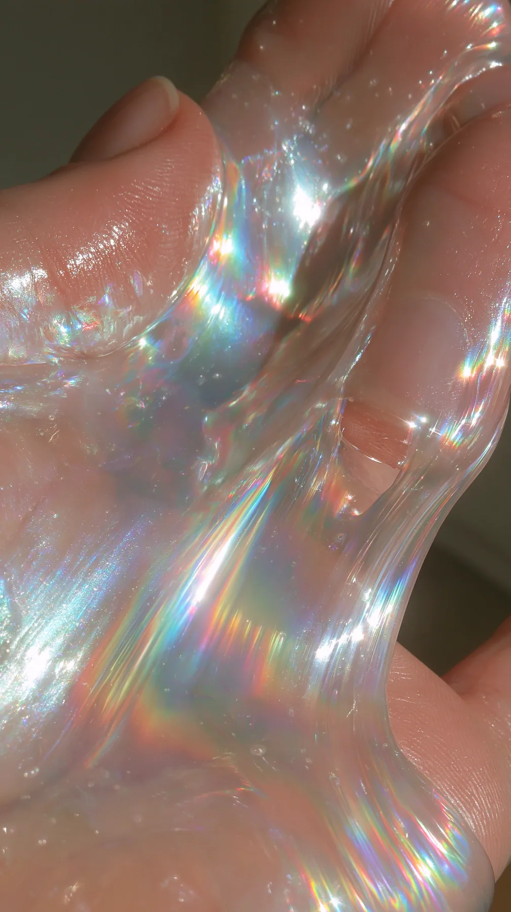 macro of iridescent slime stretched between fingers, oddly satisfying, glossy, no text, no letters, no logos