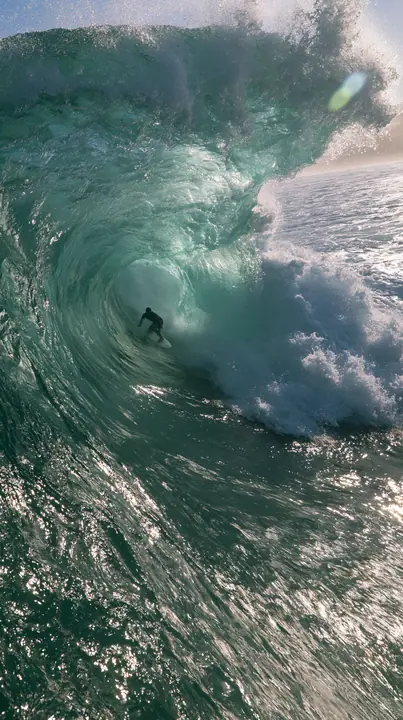 a surfer inside a glassy turquoise barrel wave, sunlit spray, editorial, no text, no letters, no logos