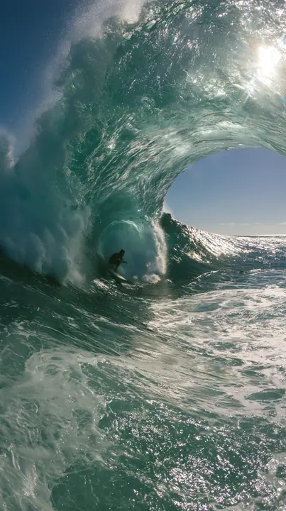 a surfer inside a glassy turquoise barrel wave, sunlit spray, editorial, no text, no letters, no logos