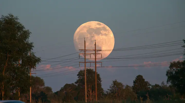 a full moon rising behind a power line at dusk, telephoto, crisp, no text, no letters, no logos