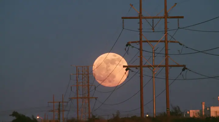 a full moon rising behind a power line at dusk, telephoto, crisp, no text, no letters, no logos