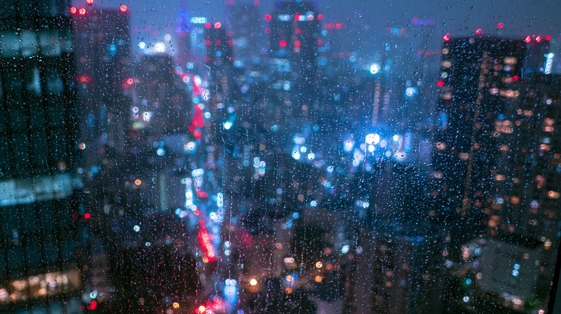a city at night seen through a rain-streaked high-rise window, neon bokeh, moody, no text, no letters, no logos