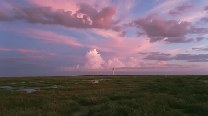 a vast flat Gulf Coast horizon in south Texas at dusk, salt marsh, a single distant launch tower, an enormous pink and violet sky, documentary photograph, no text, no letters, no logos