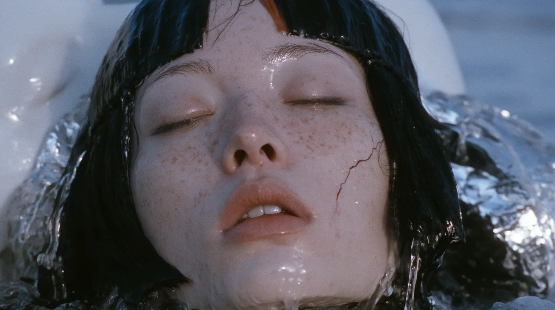 close-up of a colossal smooth white porcelain mask of a young woman's face, sculpted with a glossy black blunt bob with heavy bangs and one clay-orange streak, pale freckles, a serene expression, a hairline crack…