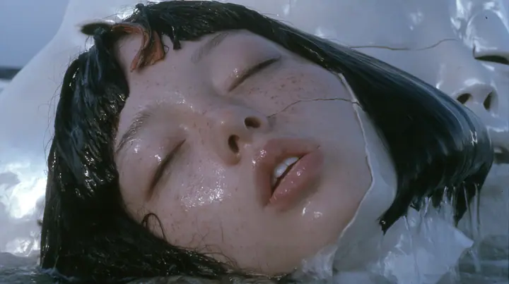 close-up of a colossal smooth white porcelain mask of a young woman's face, sculpted with a glossy black blunt bob with heavy bangs and one clay-orange streak, pale freckles, a serene expression, a hairline crack…