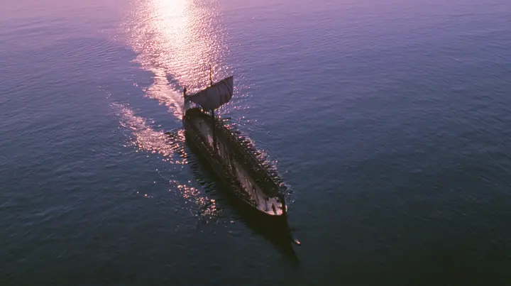 straight-down aerial of a long black ancient Greek galley with a single mast, a square sail and two banks of oars at dusk on a glassy violet sea, the two rows of oars in perfect order like lines on a page, dusk, low…