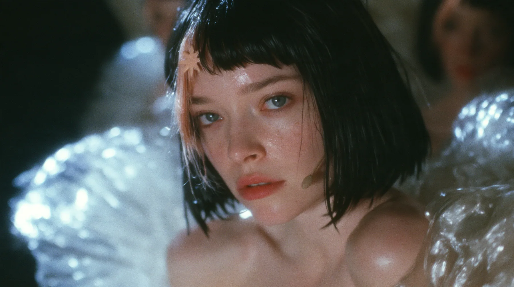 medium shot of a Caucasian American woman in her mid-twenties with pale skin and light freckles, a glossy black blunt jaw-length bob with heavy straight bangs and one clay-orange streak through the bangs, a small…