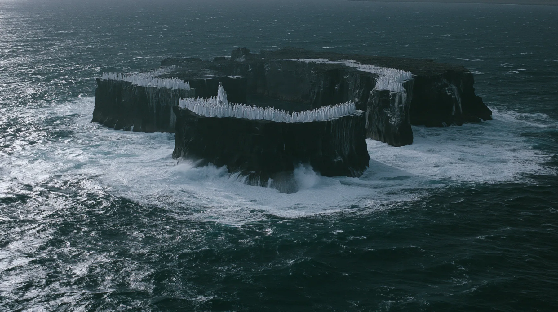 high wide aerial of a ring of black sea stacks covered with hundreds of identical pale women in white gowns, all facing the same direction, night, moonlight on a black-teal sea, silver spray, cinematic 35mm film…