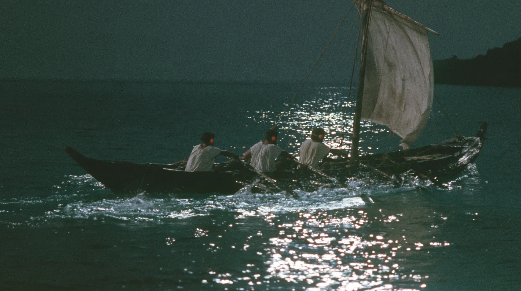 medium close-up over the gunwale of a long black ancient Greek galley with a single mast, a square sail and two banks of oars on a calm moonlit sea, three rowers in undyed linen tunics pulling the oars in time,…
