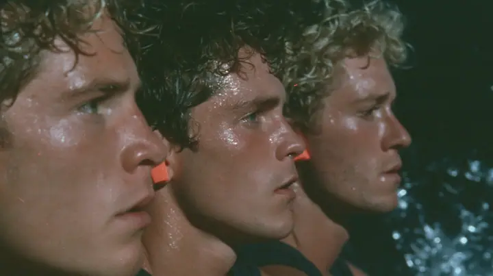 close-up of the heads of three rowers in profile at the oars of a long black ancient Greek galley with a single mast, a square sail and two banks of oars at night, bright orange foam earplugs in their ears, moonlight…