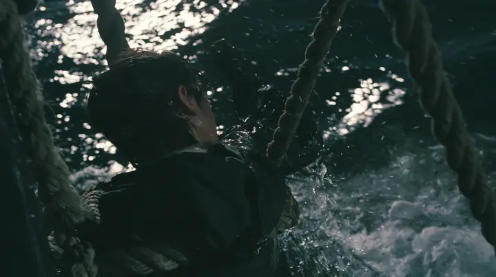 a gaunt young man in a black hoodie tied to the mast of a black ship with thick rope, night, moonlight on a black-teal sea, silver spray, cinematic 35mm film still, anamorphic, fine grain, no text, no letters, no logos