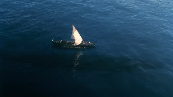 high aerial of a long black ancient Greek galley with a single mast, a square sail and two banks of oars on a darkening sea, beneath it a vast dark shadow ten times the ship's length gliding under the hull, deep blue…