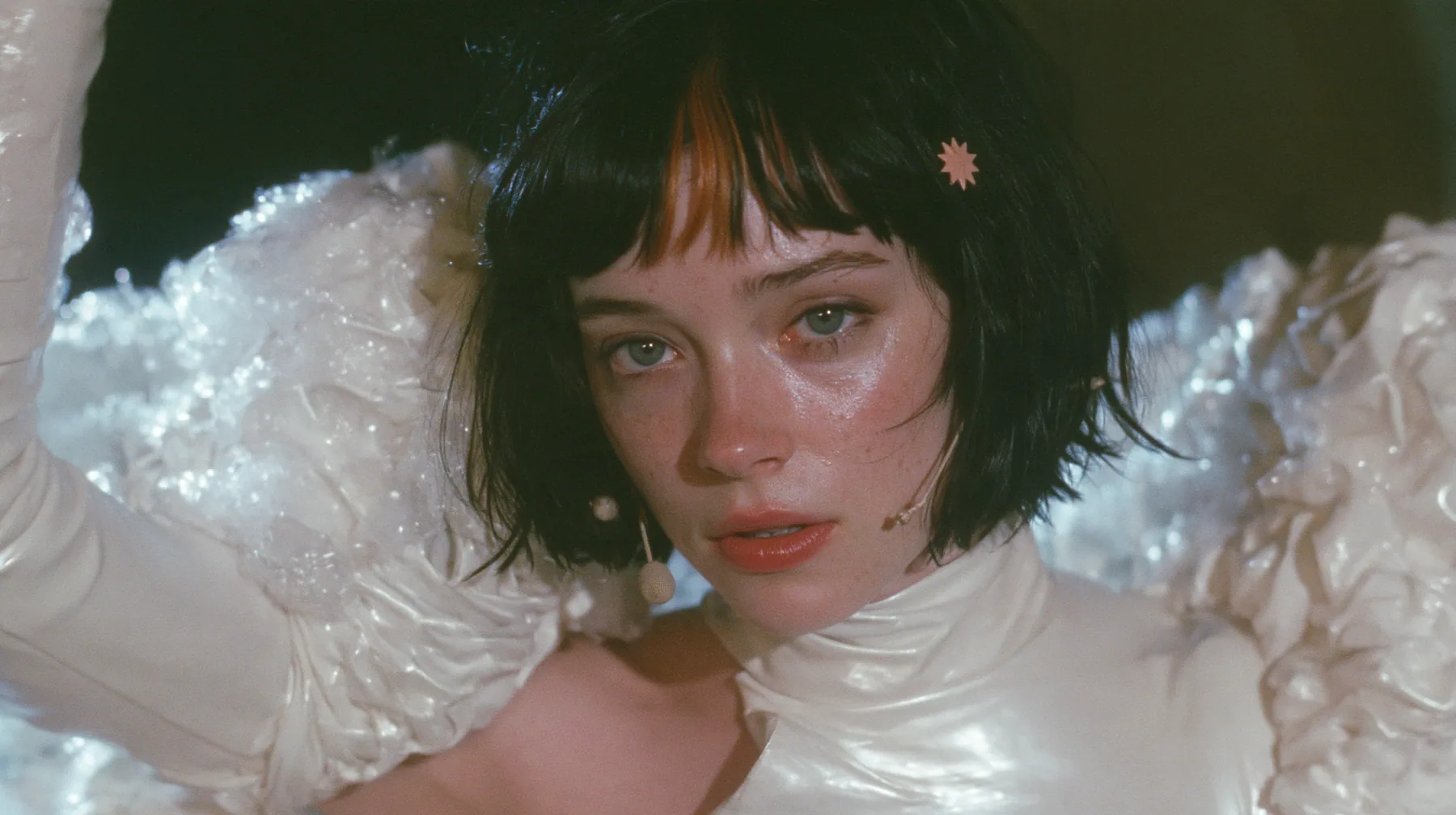 medium shot of a Caucasian American woman in her mid-twenties with pale skin and light freckles, a glossy black blunt jaw-length bob with heavy straight bangs and one clay-orange streak through the bangs, a small…